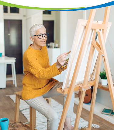 Older woman sitting indoors and painting