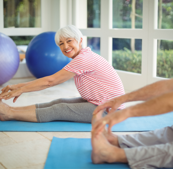 Older woman stretching on a yoga mat with partner